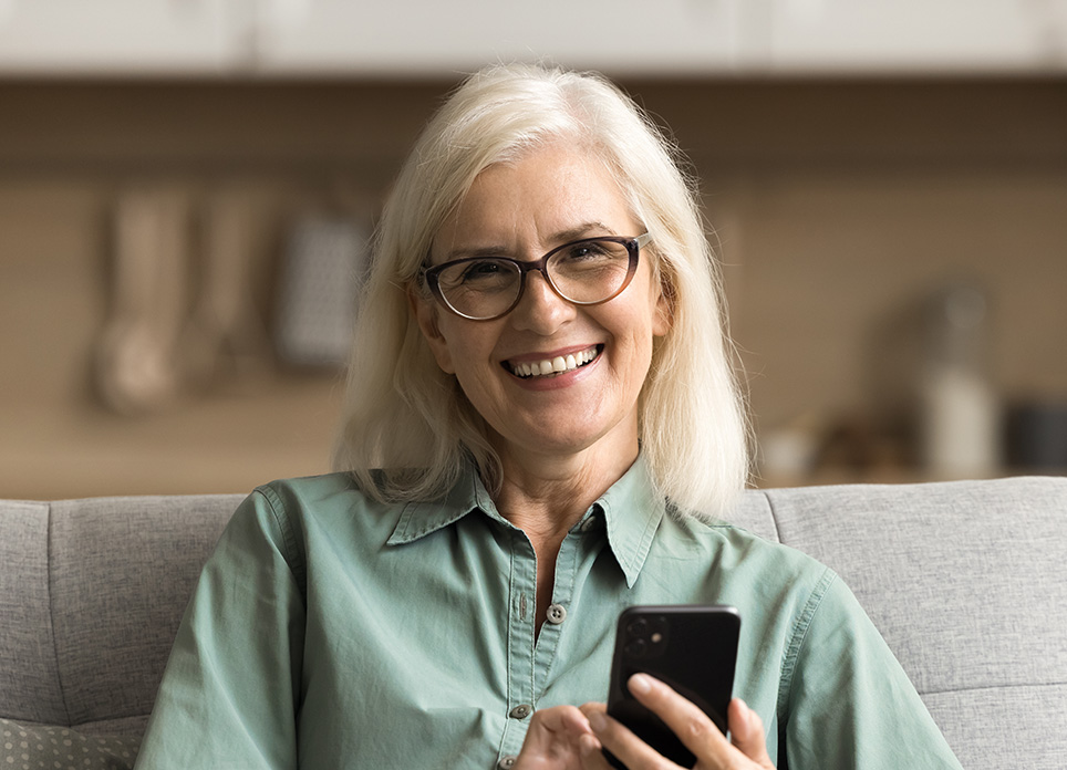 Femme sur son cellulaire souriante.